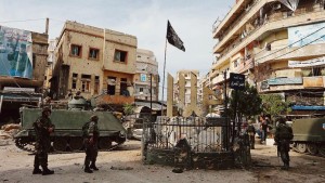 Lebanese army soldiers stand near damaged buildings after being deployed to tighten security, in Tripoli